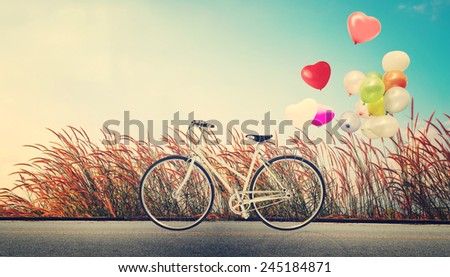 bicycle vintage with heart balloon on wild flower field and blue sky concept of love in summer and wedding honeymoon
