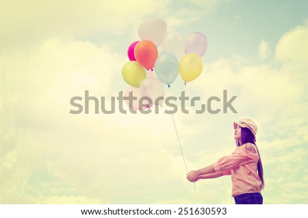 Girl hand holding multicolored balloons done with a retro vintage instagram filter effect, concept of happy birth day in summer and wedding honeymoon party (Vintage color tone paper texture)