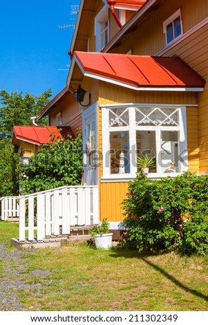 Wooden row yellow house with red roof and white windows in Scandinavian style