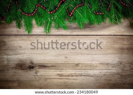 Pine tree border with red garland on old rustic wooden background