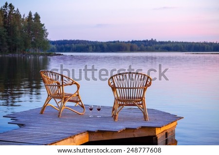 Two chairs on dock with glasses of wine