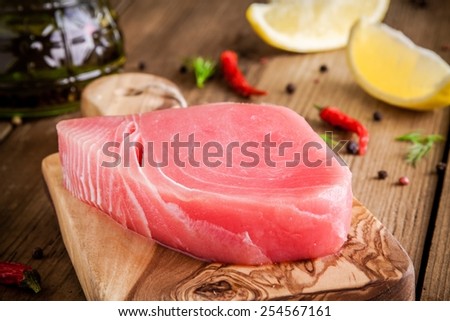 Raw tuna fillet with lemon and olive oil on cutting board