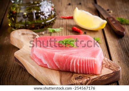 Raw tuna fillet with dill, lemon and olive oil on rustic background