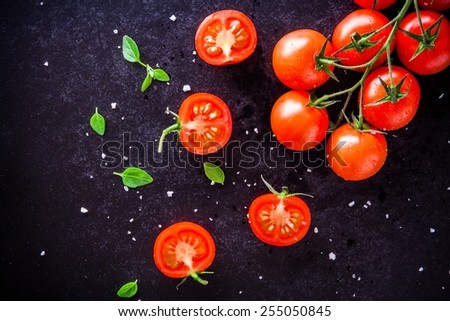 fresh organic cherry tomatoes with basil and sea salt on a dark background