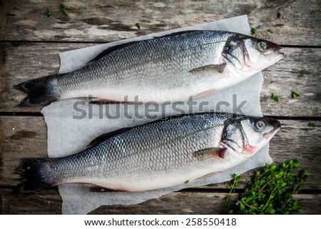 two raw sea bass with fresh thyme on wooden rustic table