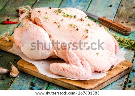 organic raw whole chicken with thyme and peppers on a rustic table
