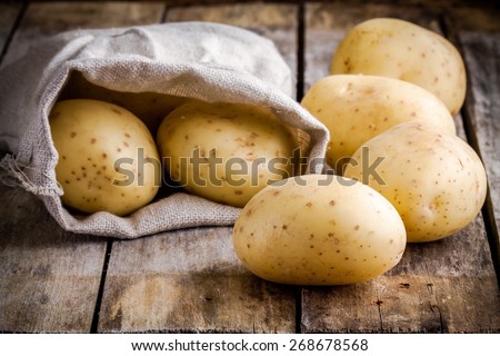 Fresh organic raw potatoes in a bag on a wooden rustic table