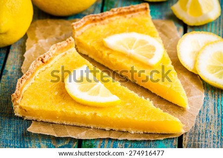 two pieces of lemon tart with slice of lemons closeup on rustic blue table
