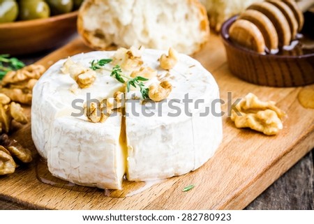 Camembert cheese with walnuts,  honey and thyme closeup on rustic table