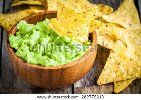 homemade guacamole with corn chips closeup on rustic wooden table