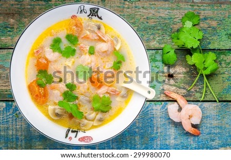 Tom Yam soup in white bowl on wooden table top view
