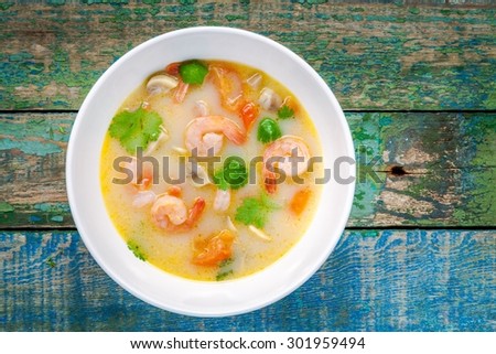 Tom Yam soup in white bowl on wooden table top view