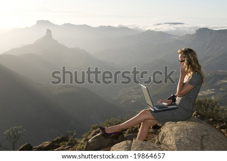 woman working with laptop in the forest and talking by phone