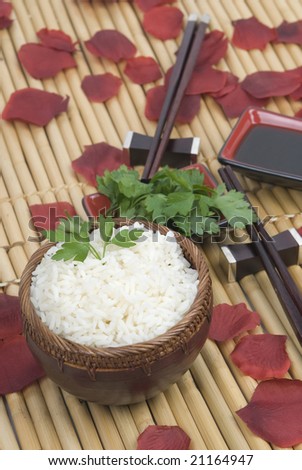 bowl of rice with oriental sticks over bamboo and roses and soja sauce