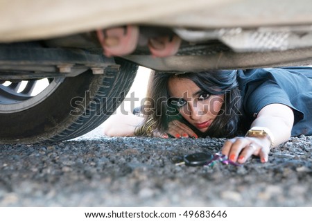 woman looking for her car key under the car