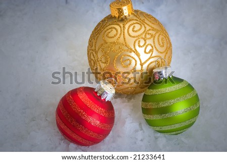 A trio of bright ornaments resting in the snow.