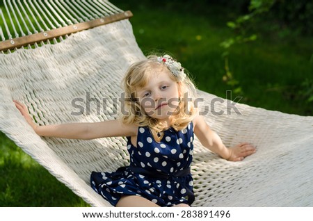 beautiful blond girl lying in white hammock