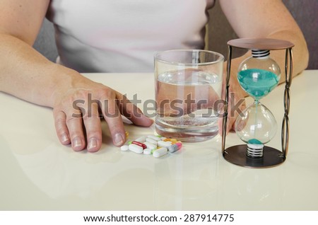 person holding pill,clock and glass of water