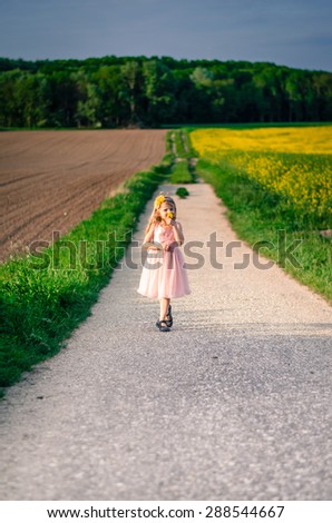 girl in pink dress walking in rural path