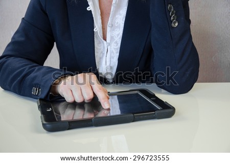 female hand typing into tablet behind working desk