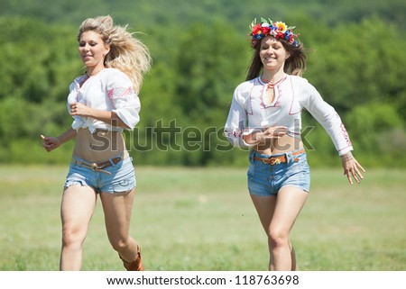 Ukrainian girls in field. Attractive young women in blouses with ukrainian embroidery running along field