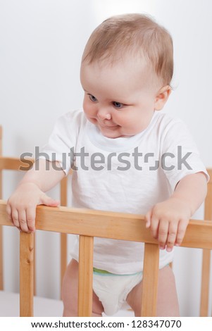 Charming child in the crib.  Charming baby stands in child bed and looking down