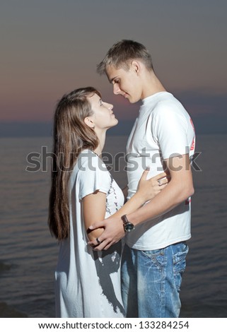 Attractive couple at the sea. Young heterosexual couple flirting on seashore in evening time