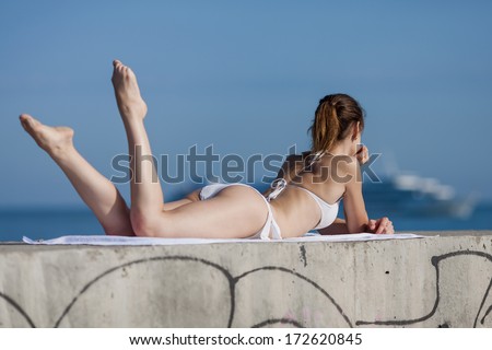 Girl at the sea. Slim girl lying down observing cruise liner
