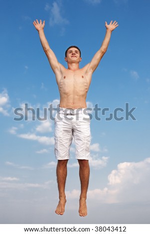 Young man in white Bermuda shorts jumping on background of the sky