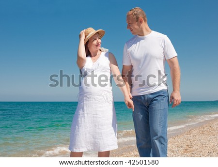 Expectant mother in hat with her husband at the sea