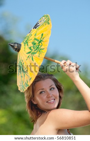 Young woman carrying yellow Chinese parasol outdoors