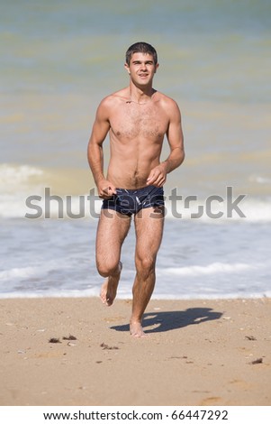 Attractive young man at the sea. Young man is running along the beach