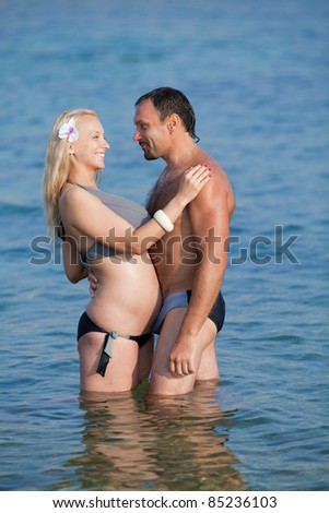 Attractive couple at the sea. Middle aged man and young pregnant woman in sea