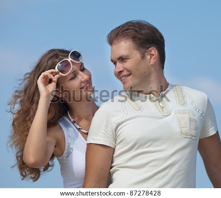 Attractive couple on pier. Young man embracing his wife smiling