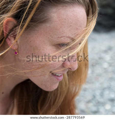 Female face with freckles. Portrait of attractive ginger girl outdoors