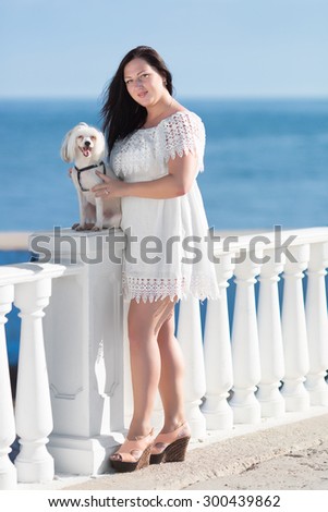 Girl with dog on seafront. Young woman with chinese crested dog on the background of the sea