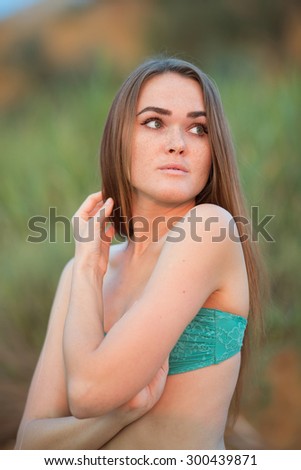 Girl looking away. Waist-up portrait of young long-haired woman in green bikini top