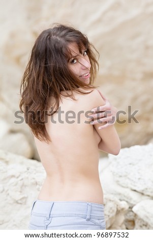 Topless young woman on open air. Back view of attractive dark haired woman hiding her naked chests under her arms