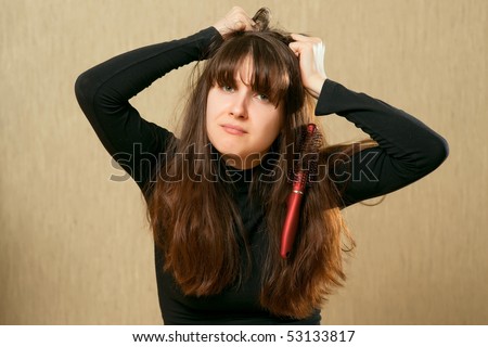 Frustrated young woman having a bad hair day with brush stucks in her hair