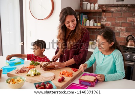 Children Helping Mother To Make School Lunches In Kitchen At Home 商業照片 © 