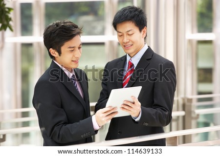 Two Chinese Businessmen Using Tablet Computer Outside Office
