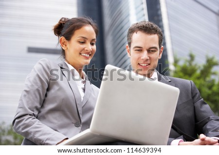 Businessman And Businesswoman Working On Laptop Outside Office