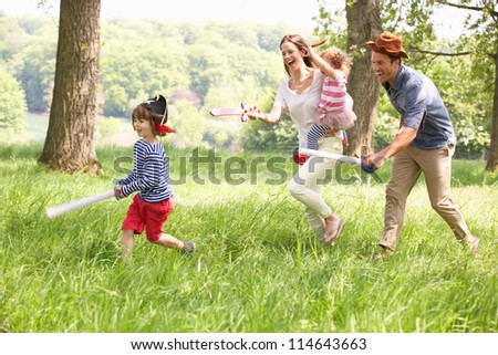 Parents Playing Exciting Adventure Game With Children In Summer Field