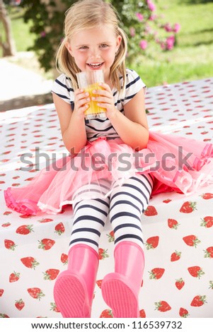 Young Girl Wearing Pink Wellington Boots Drinking Orange Juice