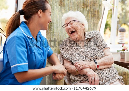 Senior Woman Sitting In Chair And Talking With Nurse In Retirement Home Foto d'archivio © 