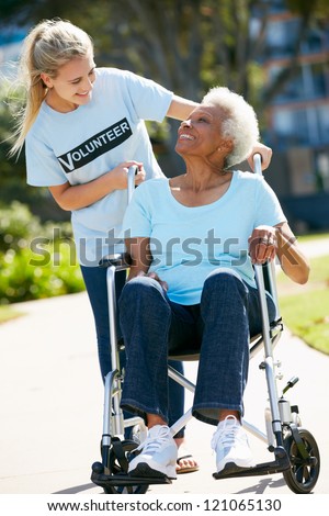 Teenage Volunteer Pushing Senior Woman In Wheelchair