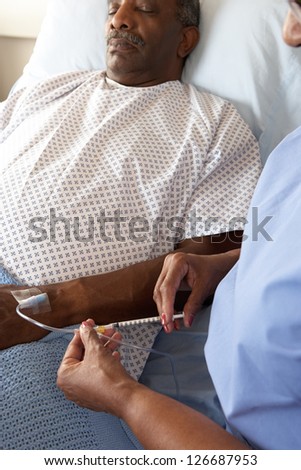 Nurse Injecting Senior Male Patient In Hospital Bed