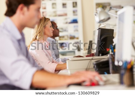 Workers At Desks In Busy Creative Office