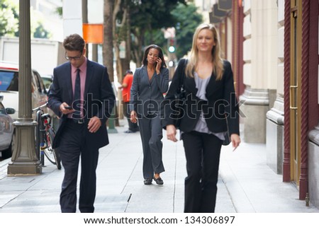 Group Of Businesspeople Walking Along Street