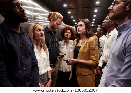 Work colleagues stand waiting together in an elevator at their office Сток-фото © 